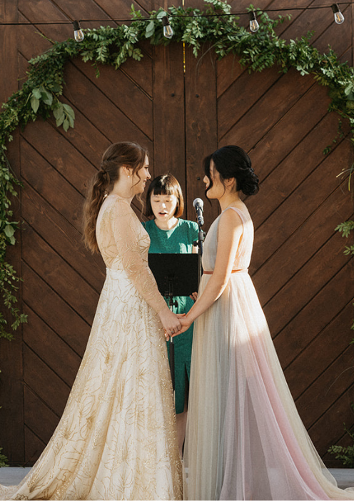 Two brides exchanging vows during a wedding ceremony at FruitCraft’s San Diego venue.